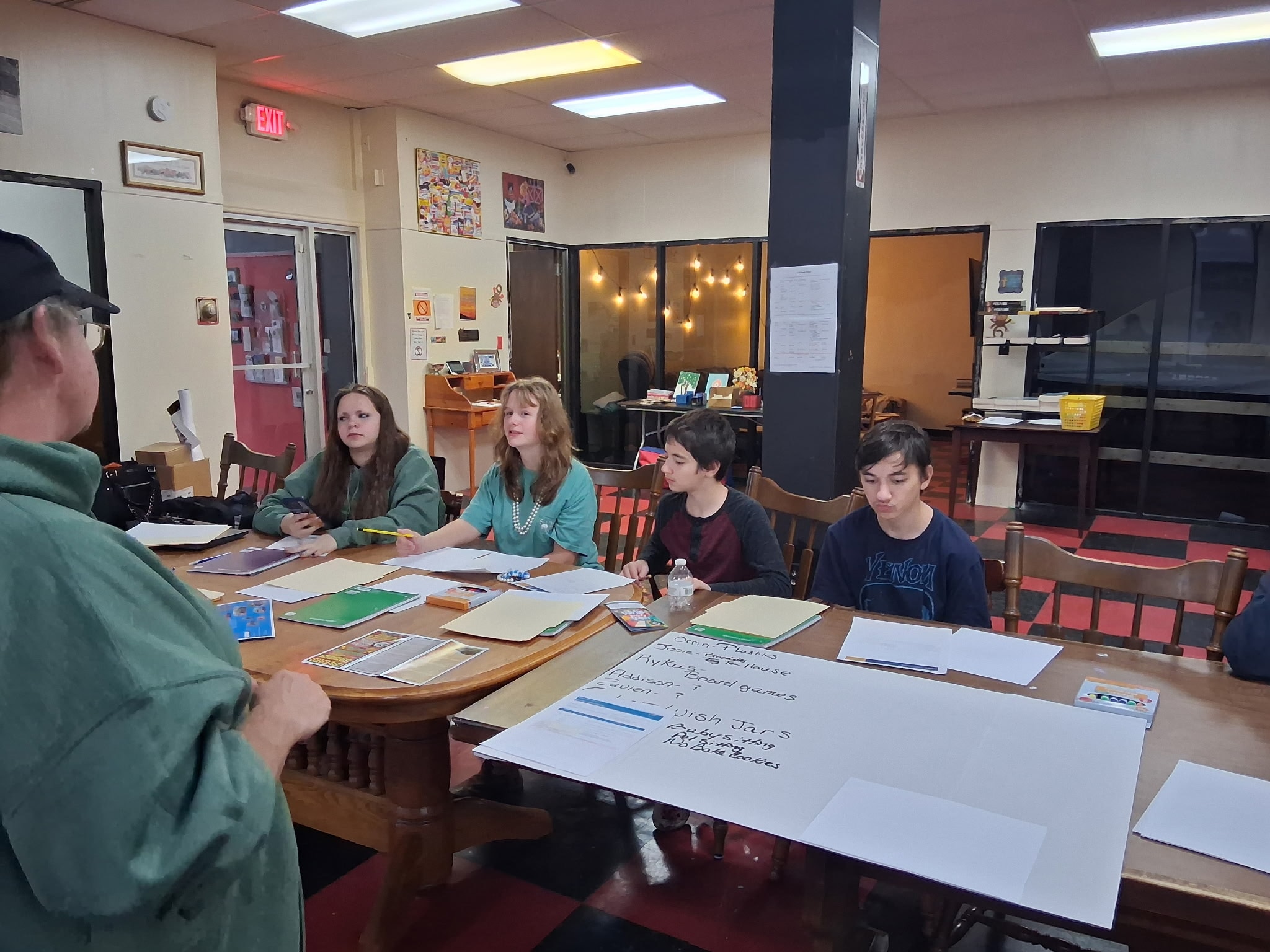 Club members around the table sharing their business ideas during the first Young Entrepreneurs Club session, with the group's idea board on the table